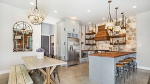 Une cuisine moderne dotée d’un îlot central, d’appareils électroménagers en acier inoxydable et d’un pare-feu en pierre rustique.