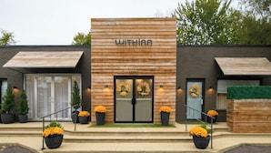 A modern hotel with a wooden facade, a double door entrance, and potted plants on the steps. - Getaway WithInn-Relaxation Centrally Located to Beaches and Walkable Restaurants (Harbert)