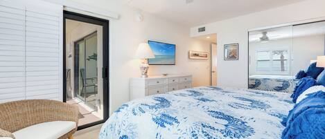 Un dormitorio con cama, una silla, un tocador y una puerta que da a un balcón.