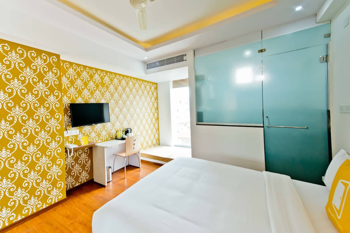 Une chambre d’hôtel comprenant un lit, un bureau avec une chaise, une télévision et une armoire.