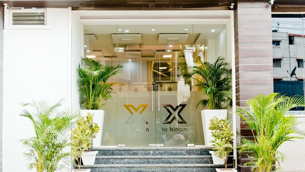 En butiksfasad med skylten ”by bloom” och en logotyp som föreställer ett stiliserat ”X”.