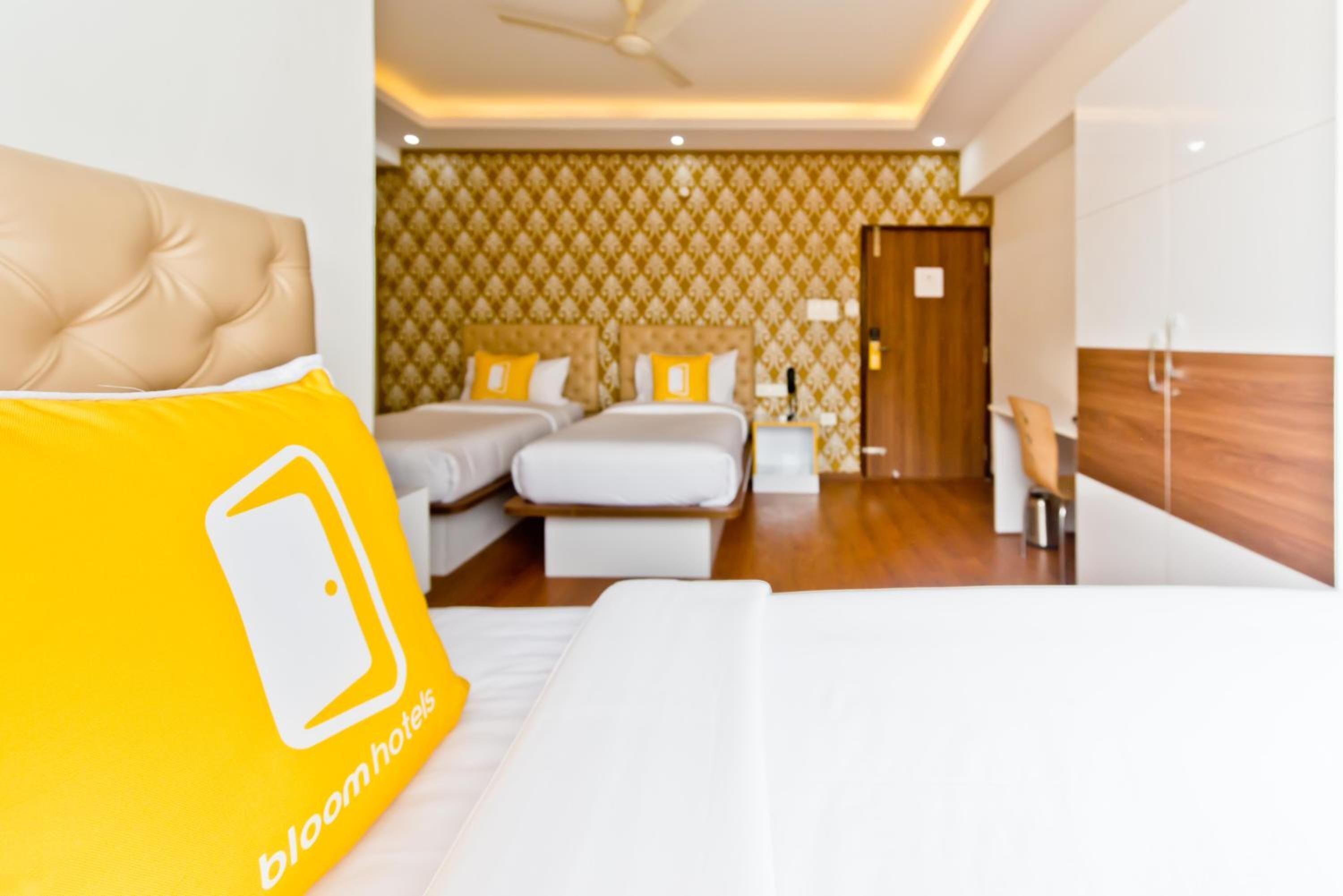 A hotel room with a large bed, two bedside tables, a wooden headboard, and a patterned wallpaper.