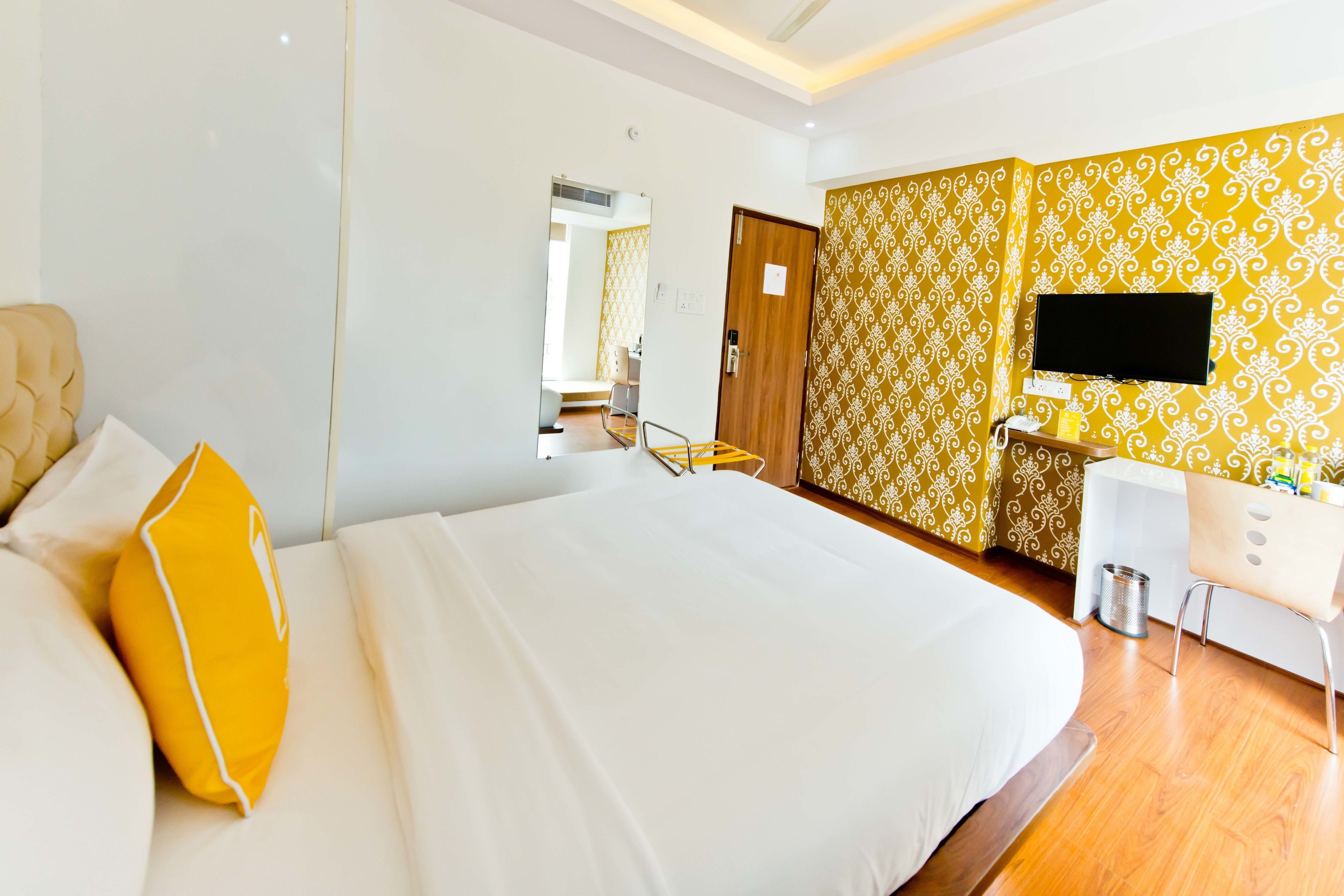 Una habitación de hotel con una cama grande, un escritorio, una silla y un televisor montado en la pared.