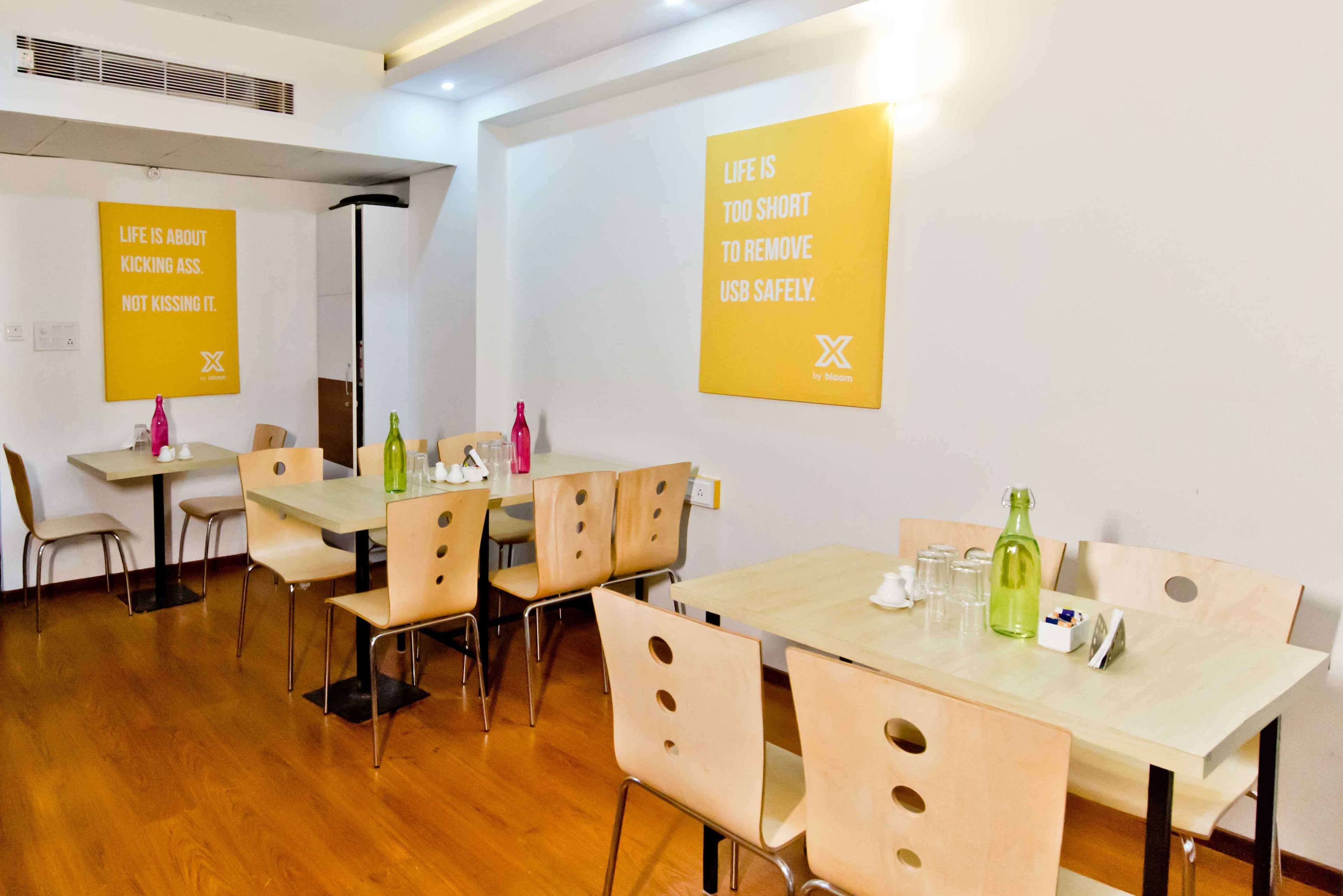 A modern conference room with wooden tables and chairs, equipped with water bottles and glasses.