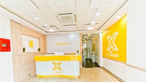 Ett receptionsområde med en gul och vit disk där logotypen ”X by bloom” visas.