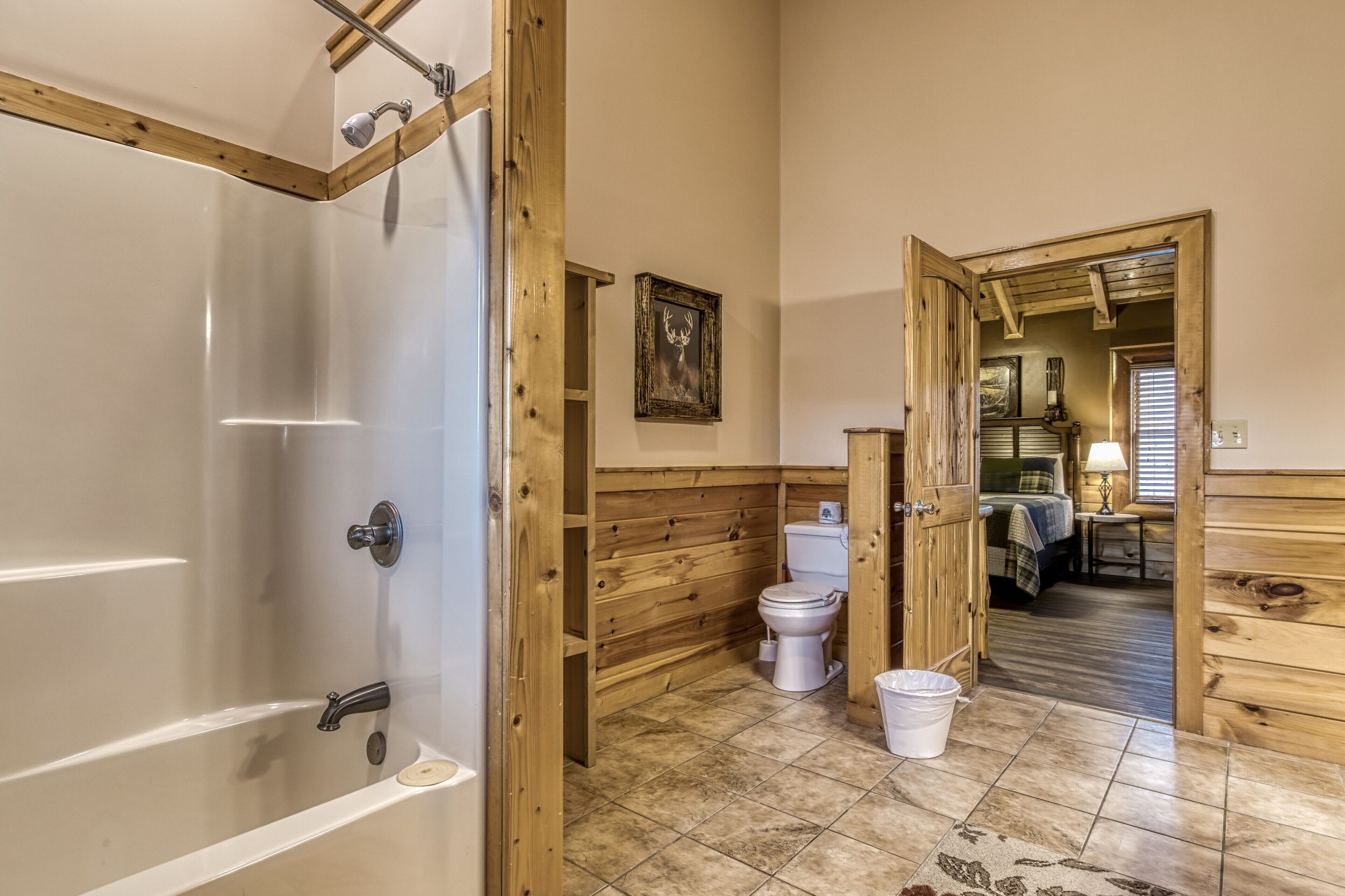 Une salle de bain aux murs lambrissés, équipée d’une baignoire, de toilettes et d’une douche.