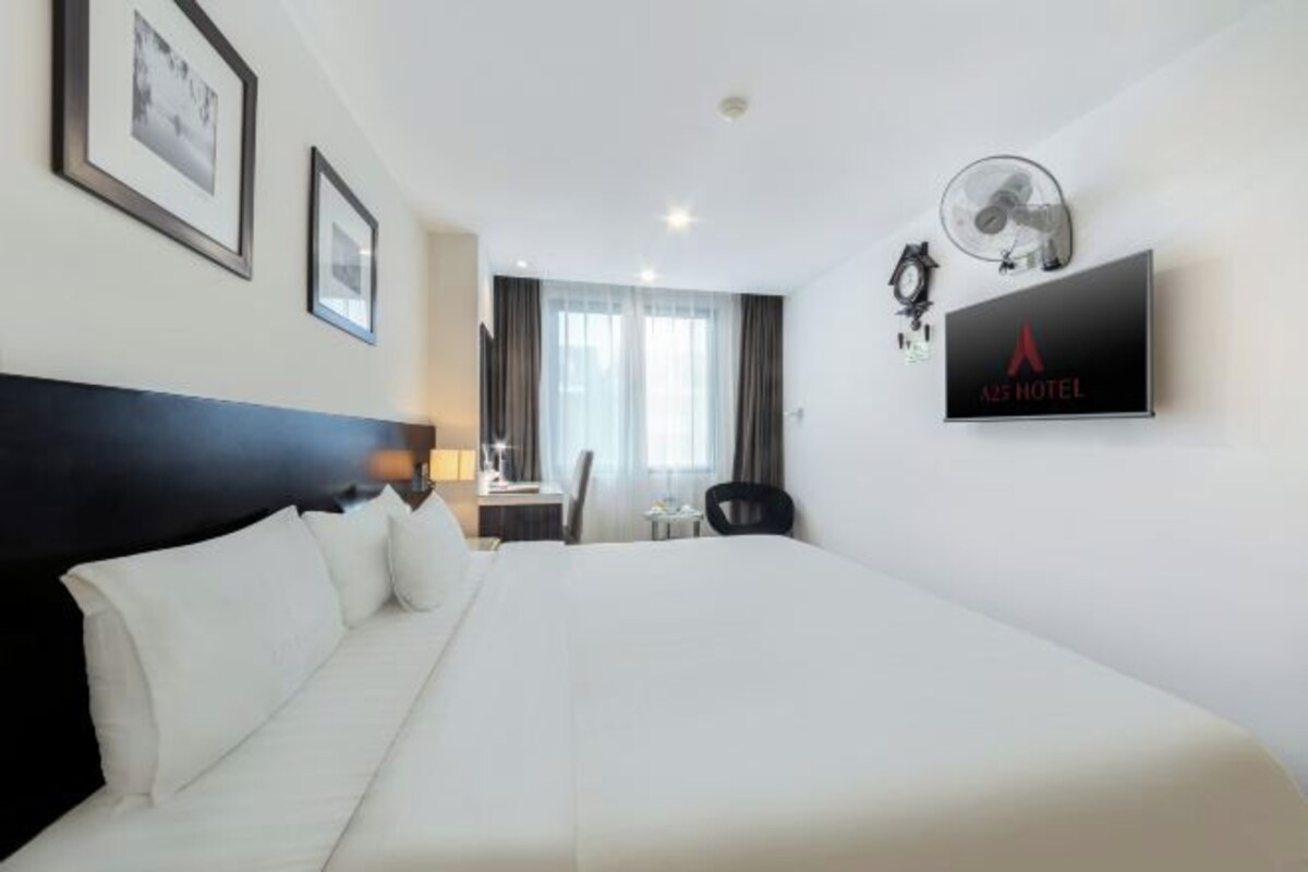 Habitación de hotel con una cama grande, un escritorio, una silla y un televisor montado en la pared.