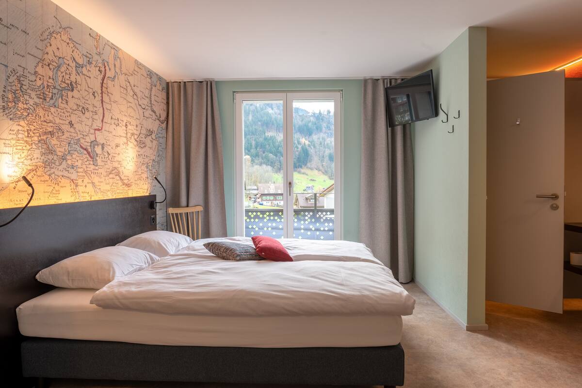 Un dormitorio con una cama grande, un mapa en la pared, un televisor y vistas al exterior.
