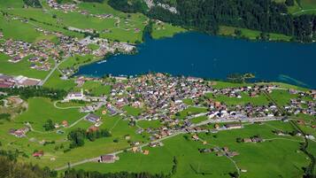Vista aerea di una piccola cittadina con un lago, circondata da campi verdi e zone residenziali.