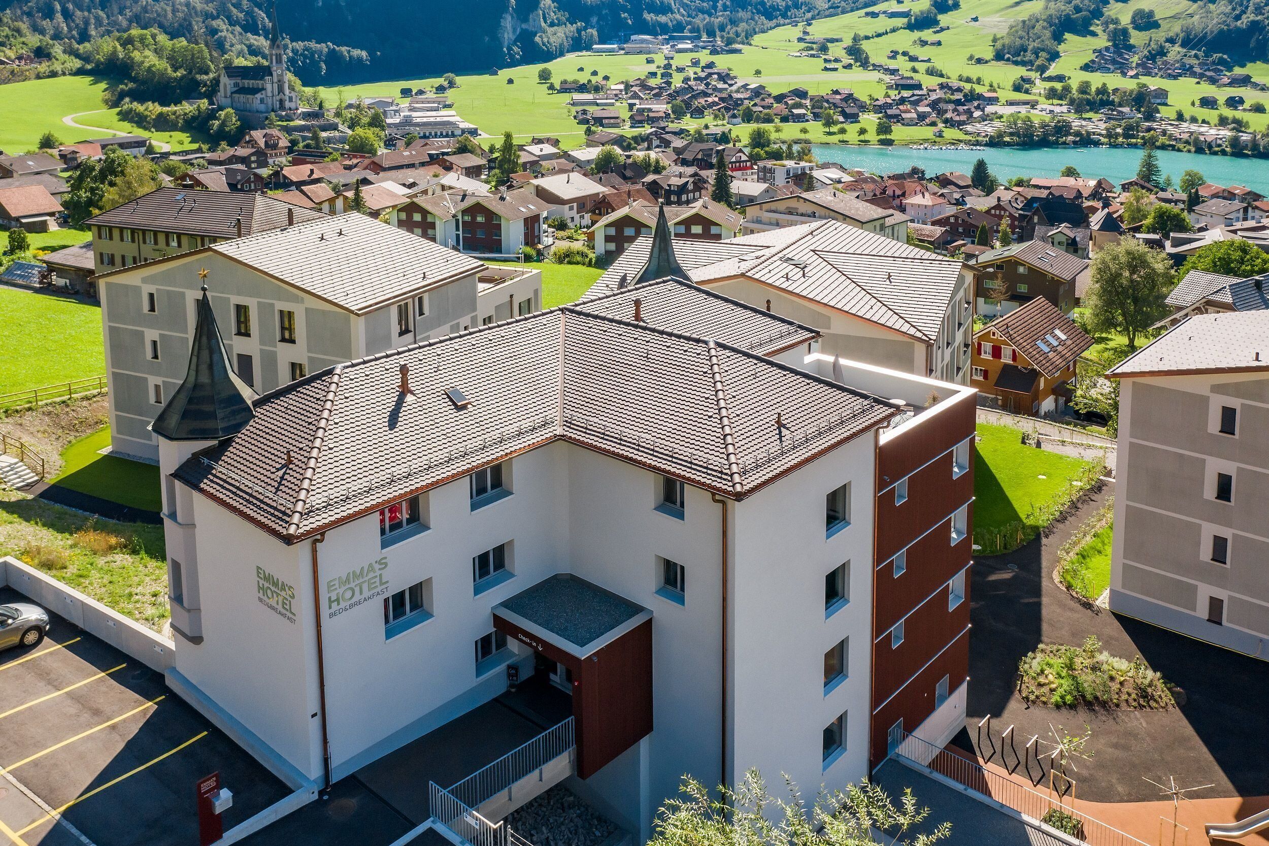 A hotel with a modern design, a parking lot, and a view of a lake and surrounding buildings.