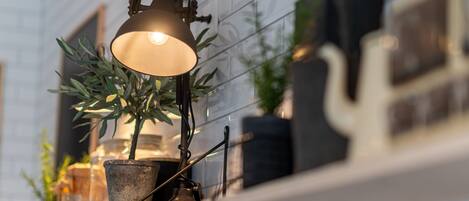 A kitchen with a hanging pendant light, a potted plant, and a microwave on the counter.