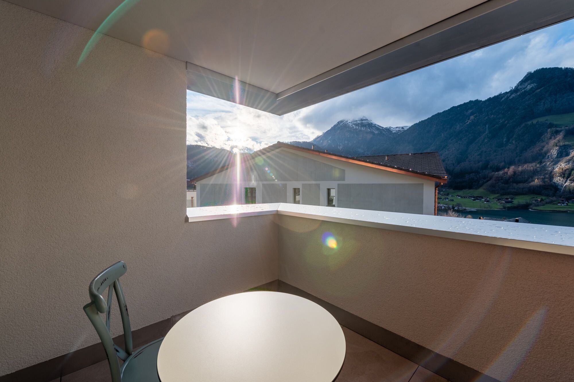 Ein Balkon mit Blick auf Berge und einen See, ein runder Tisch und ein Stuhl.