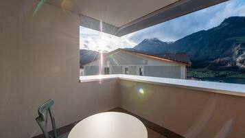 Ein Balkon mit Blick auf Berge und einen See, ein runder Tisch und ein Stuhl.