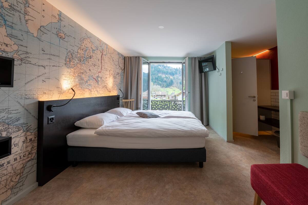 Un dormitorio con una cama grande, un mapa en la pared, un televisor y vistas al exterior.