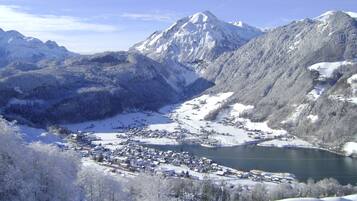 A snow-covered mountain landscape with a town nestled at the base, surrounded by snow-covered trees and a lake.