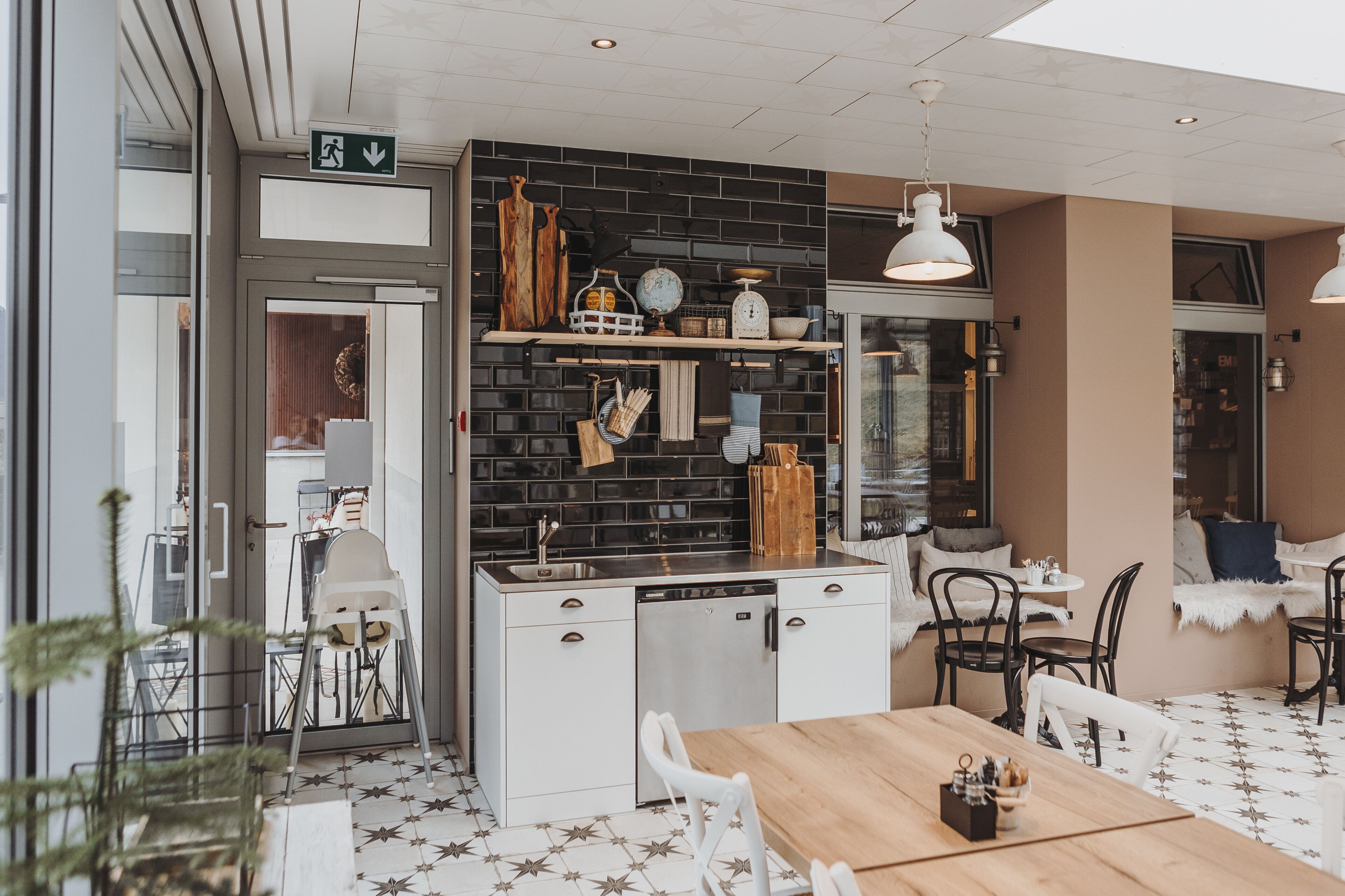 Une cuisine compacte avec un plan de travail noir, des armoires blanches et un coin repas comprenant une table et des chaises en bois.