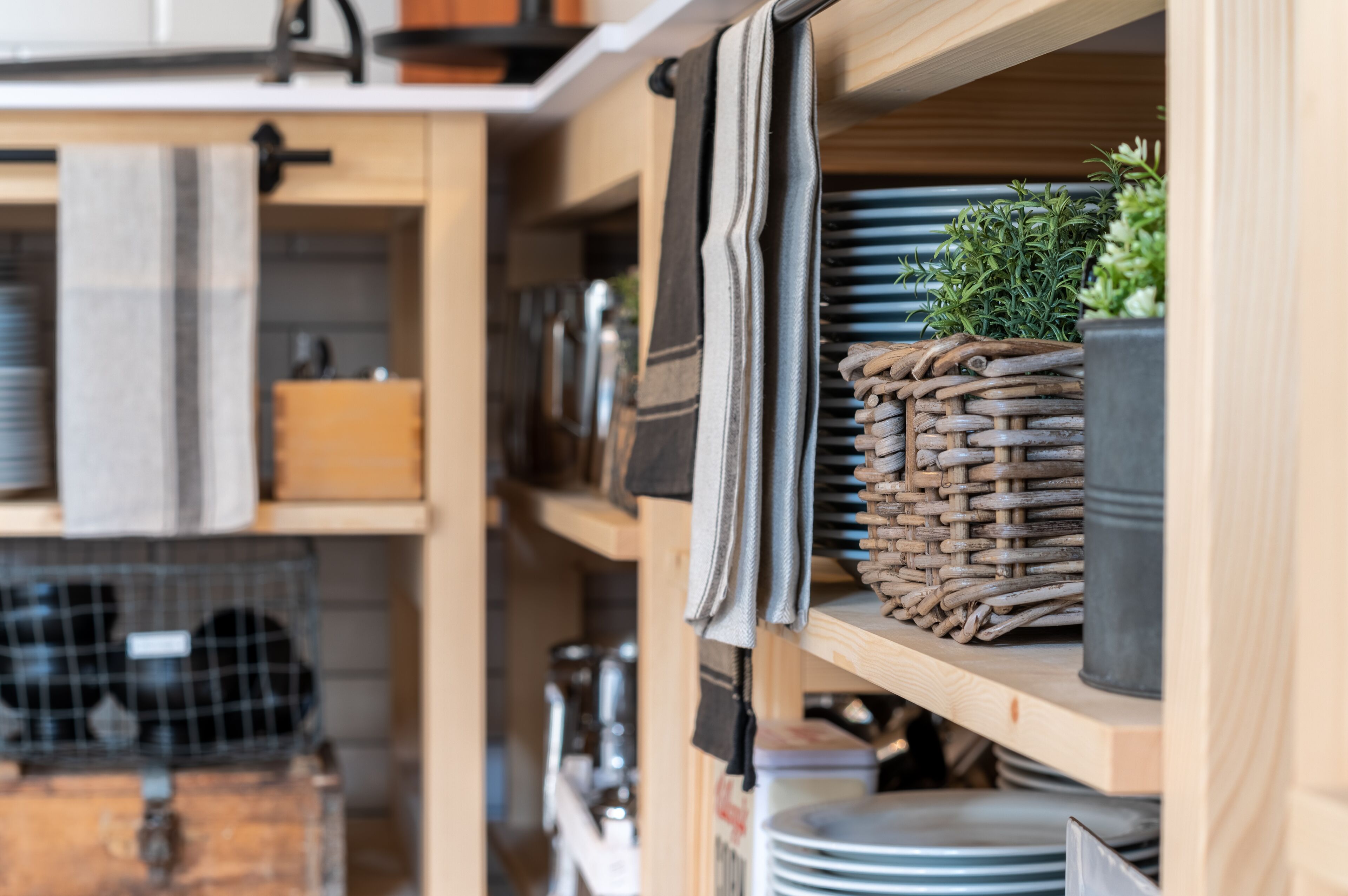 Una cocina con estantes de madera, una cesta tejida y una planta en maceta.