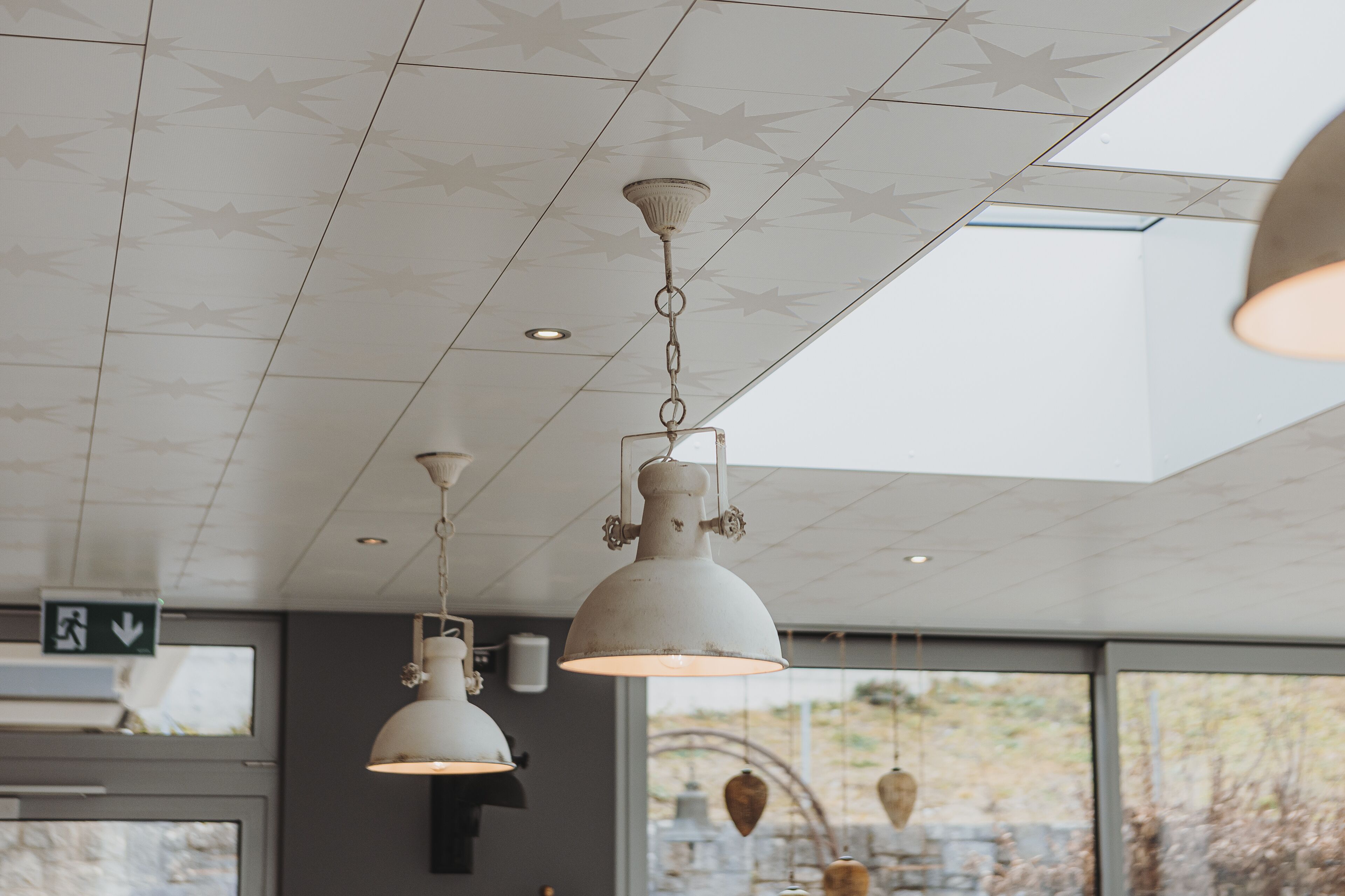 A ceiling with star patterns, pendant lights, and a view of the outdoors through large windows.