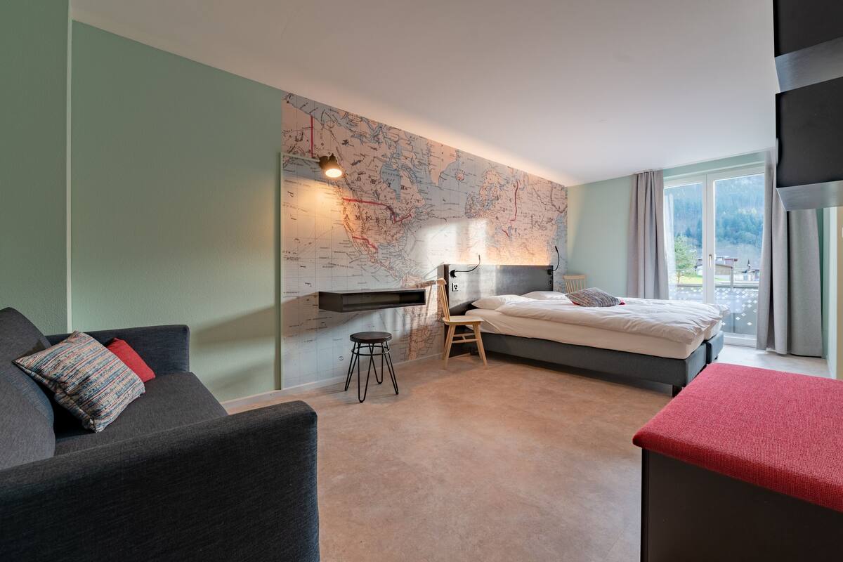 Una habitación de hotel moderna con una cama grande, un escritorio y un mapa en la pared.