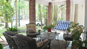A covered patio with outdoor furniture, a hanging swing, and a view of the street. - Home Away From Home,  pet friendly retreat! (Ocean Pines)