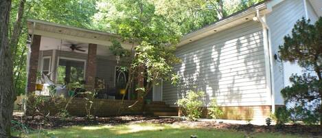 A single-story house with a covered porch, a small front yard, and a tree in front.