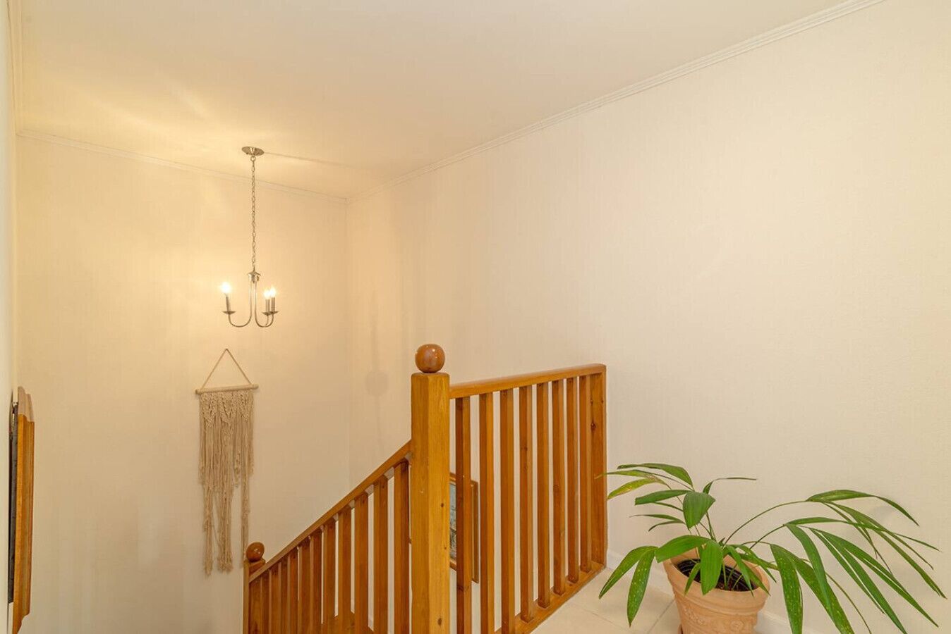 Un escalier avec des rampes en bois et une décoration murale en macramé suspendue.