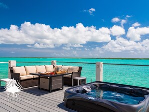 Relax on the deck with a hot tub and dining area overlooking the turquoise sea.