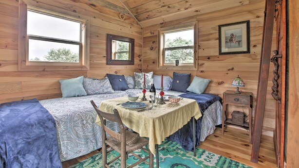 A cozy cabin room with wooden walls, two beds, a dining table, and a small side table. - Blue Ridge Nature Lovers retreat (Callaway)