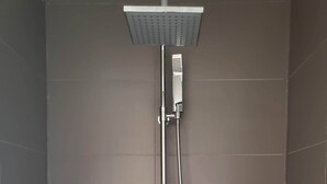Une cabine de douche dotée d’un pommeau de douche carré et d’un flexible de douche.