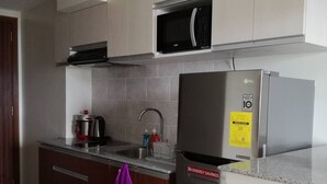 Una cucina moderna con un frigorifero in acciaio inossidabile, un forno a microonde e un bollitore sul piano di lavoro.