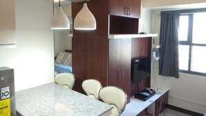 Una moderna camera d'albergo con un piano di lavoro in granito, due lampade a sospensione, una TV e un'ampia finestra con tende.