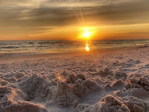 A beach with sand dunes and a sunset in the background.