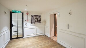 A hallway with a wooden floor, a door labeled "KELUAR," a framed picture on the wall, and a lamp. - OYO Home 44050 Essential Studio Empire Marriot (Petaling Jaya)