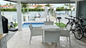 A covered outdoor patio with a pool, white furniture, and bicycles. - Dream Vacation Home Key Colony Beach Marathon Now with private pool! (Marathon)