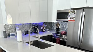 A modern kitchen with a large island, stainless steel appliances, and bar stools. - Dream Vacation Home Key Colony Beach Marathon Now with private pool! (Marathon)
