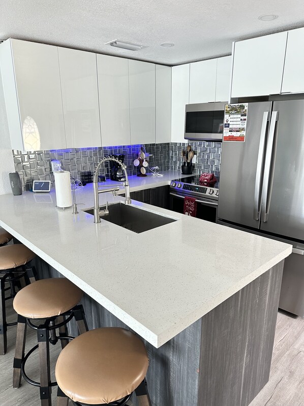 A modern kitchen with a large island, stainless steel appliances, and bar stools. - Dream Vacation Home Key Colony Beach Marathon Now with private pool! (Marathon)