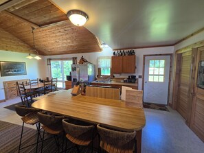 A kitchen with a wooden table and chairs, a refrigerator, and a sink.
