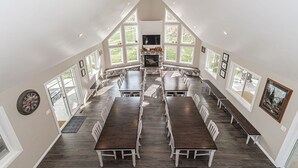 A spacious dining area with high ceilings and large windows, featuring a fireplace and a ceiling fan.