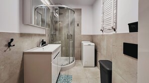 Een moderne badkamer met een douchecabine van glas, een wit wastafelmeubel, een toilet en een zwarte prullenbak.