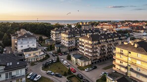 A residential area with multi-story apartment buildings, a parking lot, and a view of the sea. - Sun & Snow Na Wydmie (Ustka)