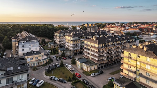 A residential area with multi-story apartment buildings, a parking lot, and a view of the sea. - Sun & Snow Na Wydmie (Ustka)