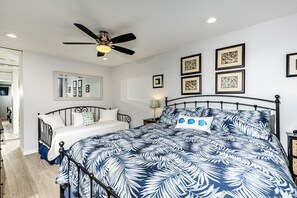 A bedroom with a bed, a ceiling fan, a mirror, and framed artwork on the wall. - Spectacular garden views. A short walk to the beach, restaurants, and shops! (Oceanside)