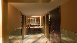 A hotel corridor with mirrored walls, a patterned carpet, and a green exit sign. - Fu Yi Fashion Hotel (Chongqing)