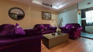 A modern hotel lobby with purple sofas, a coffee table, a mirror, and a framed picture on the wall. - Fu Yi Fashion Hotel (Chongqing)