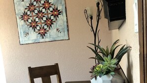 A dining area with a wooden table and chairs, a wall-mounted painting, a potted plant, and a wall-mounted light fixture. - Main house in the heart of Sedona (Sedona)