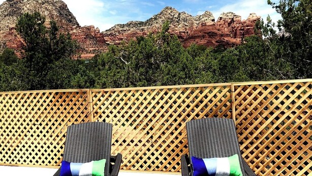 Two lounge chairs with cushions, a wooden lattice fence, and a view of red rock formations. - Main house in the heart of Sedona (Sedona)