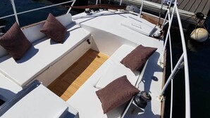 Un ponte di nave con zone relax, pavimento in legno e ringhiera bianca.