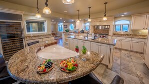 A spacious kitchen with granite countertops, a central island, and pendant lighting.