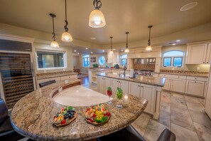 A spacious kitchen with granite countertops, a central island, and pendant lighting.