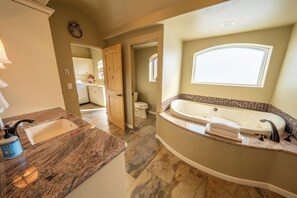 Een badkamer met een groot bad, een wastafel en een toilet.